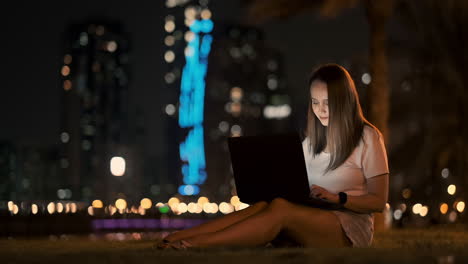 Joven-Y-Hermosa-Diseñadora-Trabajando-Remotamente-En-Una-Computadora-Portátil-En-La-Calle-En-Verano-Bajo-Palmeras-Por-La-Noche-En-El-Parque-De-La-Ciudad.-Emiratos-Árabes-Unidos-Mujer-Europea-En-La-Noche-En-Dubai